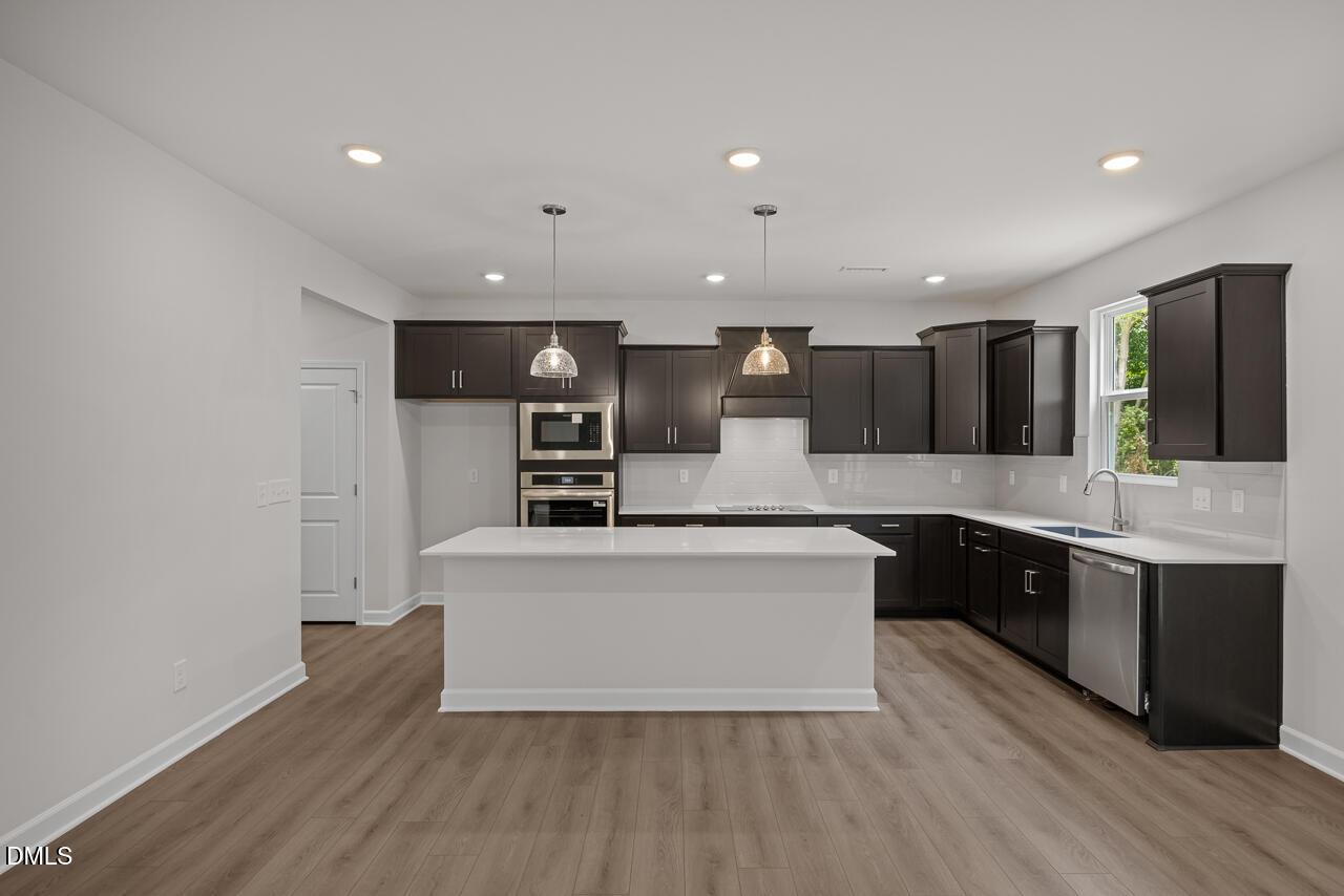 Modern kitchen with dark cabinets, white quartz island, and stainless appliances in The Hickory II B, Wellers Knoll home.