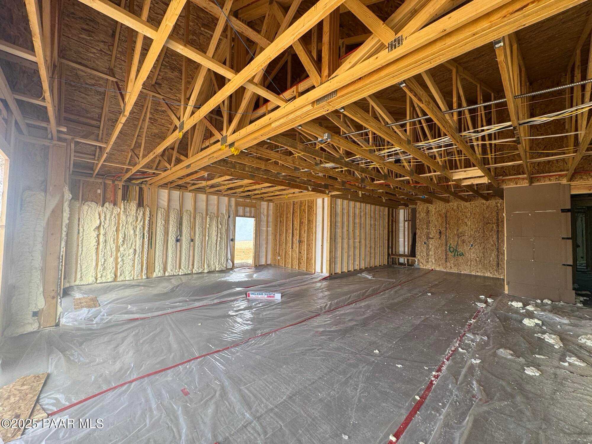 Spacious 4-car garage under construction with exposed wooden trusses and insulated walls in Evermore Homes Sunrise A, Prescott Valley