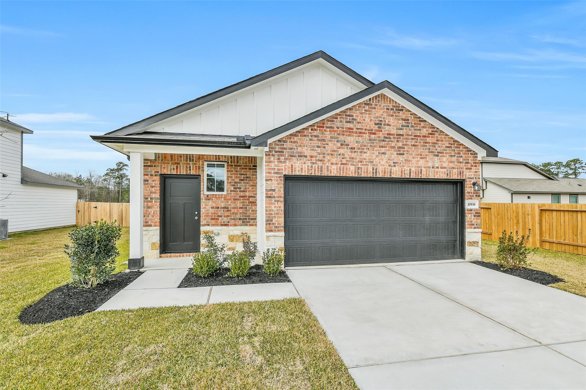 Modern brick 1-story home with black front door, 2-car garage, and landscaped front yard in Liberty Estates, Cleveland, Texas