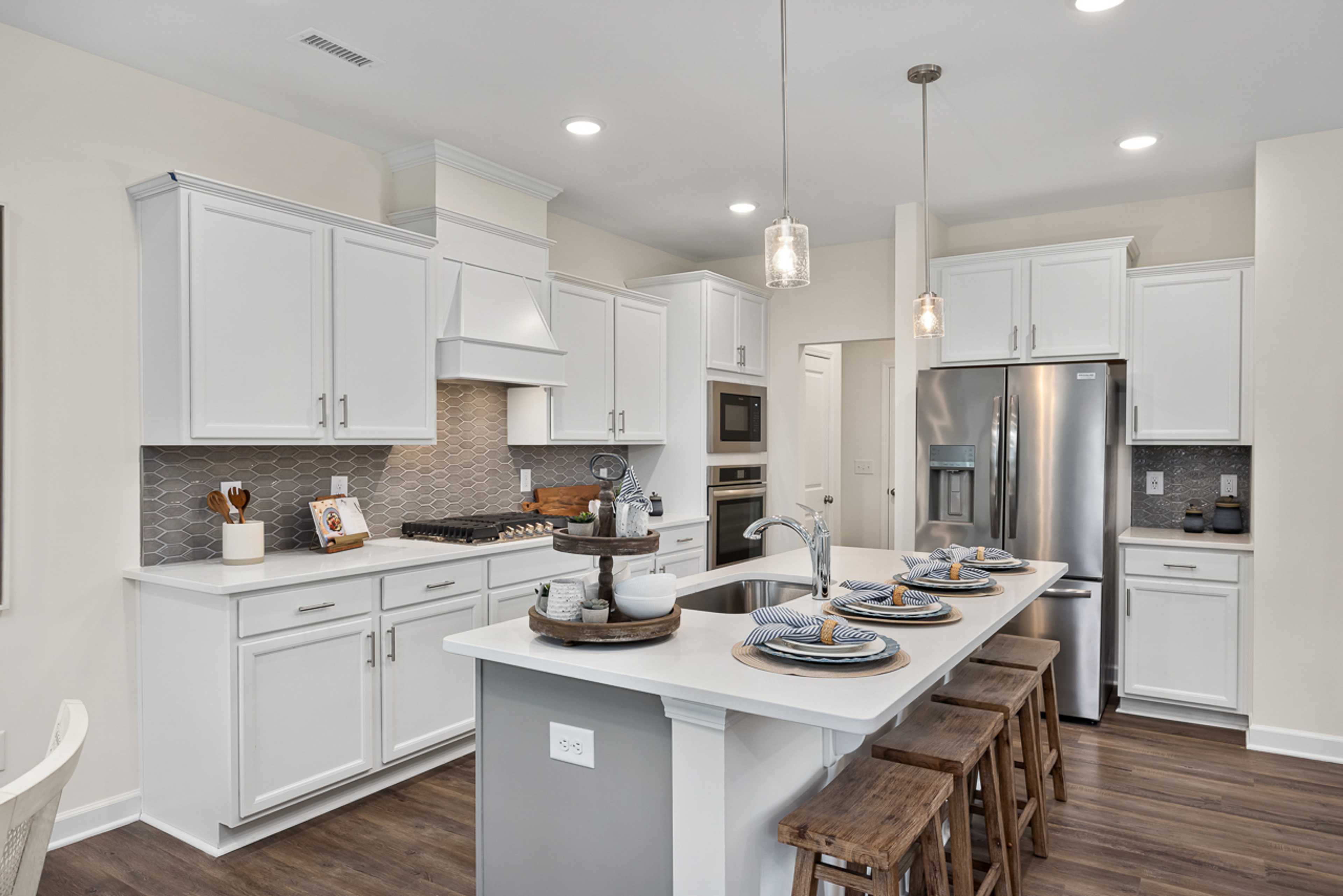 Modern white kitchen in Camden Park, Knightdale NC with shaker cabinets, large island bar, stainless steel appliances, hardwood floors