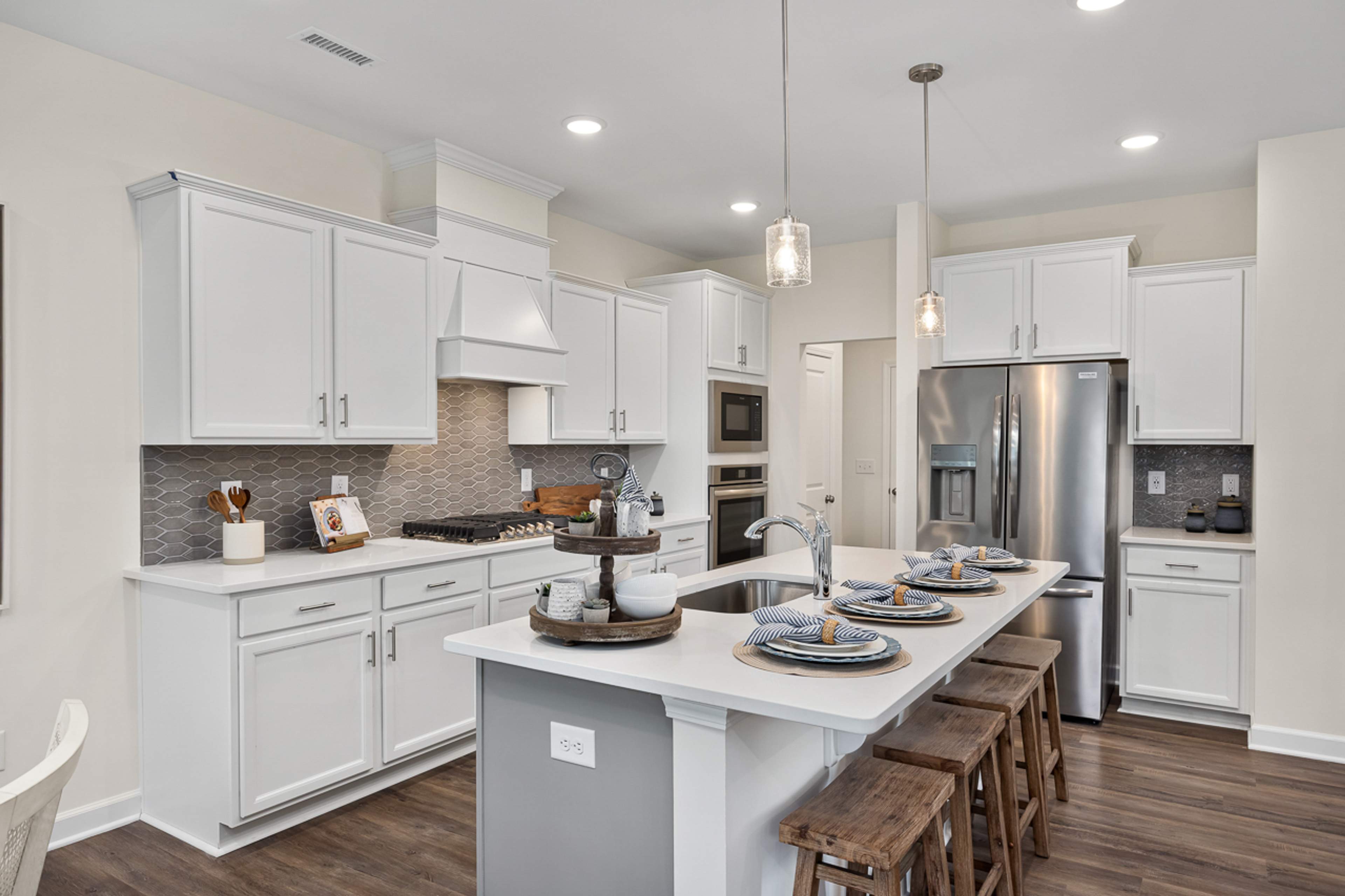 Modern white kitchen in Camden Park, Knightdale NC with shaker cabinets, large island bar, stainless steel appliances, hardwood floors