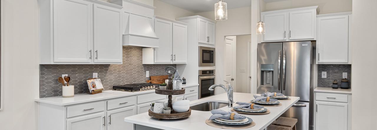 Modern white kitchen in Camden Park, Knightdale NC with shaker cabinets, large island bar, stainless steel appliances, hardwood floors