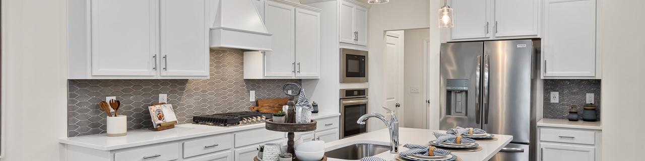 Modern white kitchen in Camden Park, Knightdale NC with shaker cabinets, large island bar, stainless steel appliances, hardwood floors