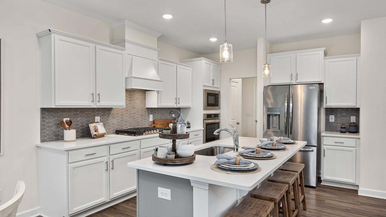 Modern white kitchen in Camden Park, Knightdale NC with shaker cabinets, large island bar, stainless steel appliances, hardwood floors