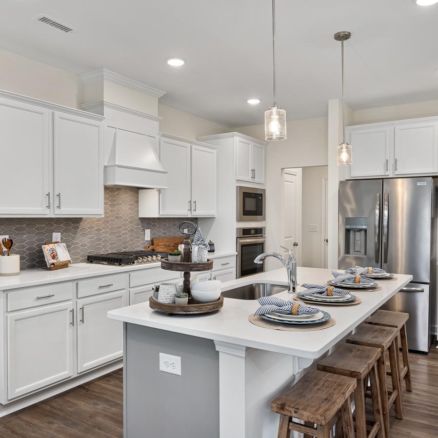 Modern white kitchen in Camden Park, Knightdale NC with shaker cabinets, large island bar, stainless steel appliances, hardwood floors