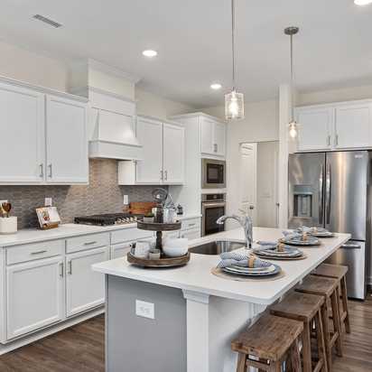 Modern white kitchen in Camden Park, Knightdale NC with shaker cabinets, large island bar, stainless steel appliances, hardwood floors