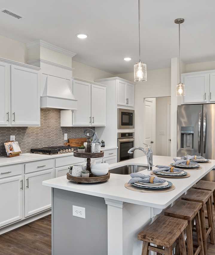 Modern white kitchen in Camden Park, Knightdale NC with shaker cabinets, large island bar, stainless steel appliances, hardwood floors