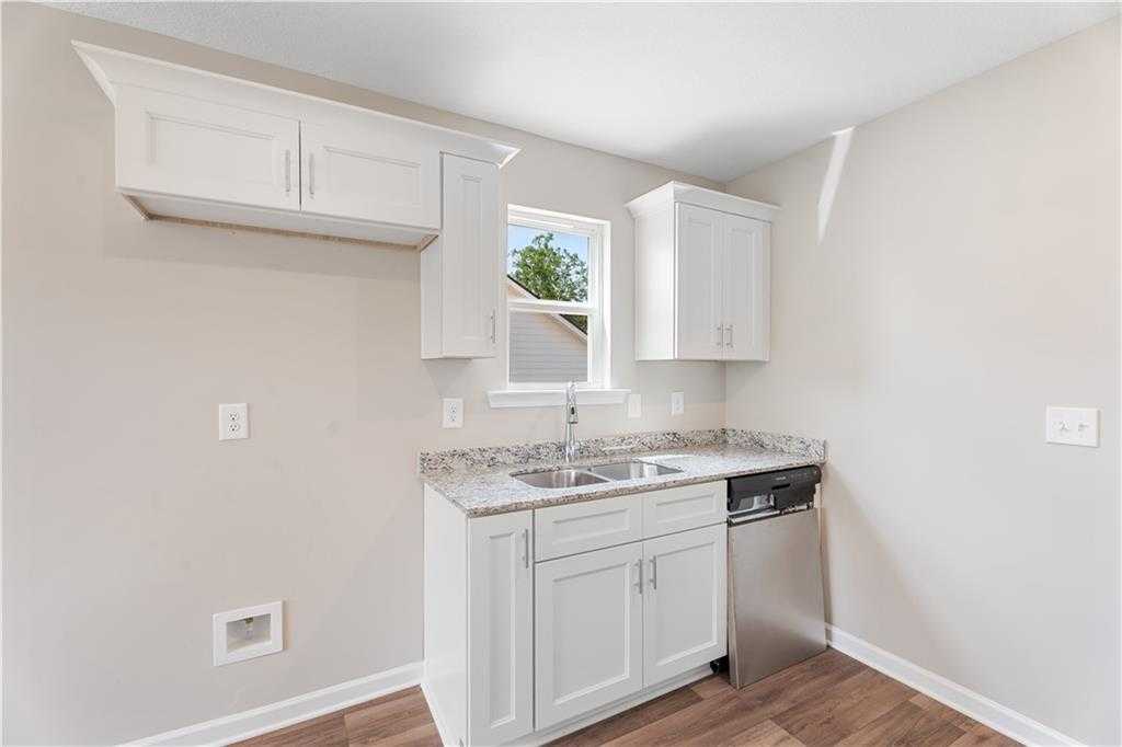 Modern white kitchen with granite countertops, stainless sink, dishwasher in Evermore Homes The Washington, Phenix City, Alabama