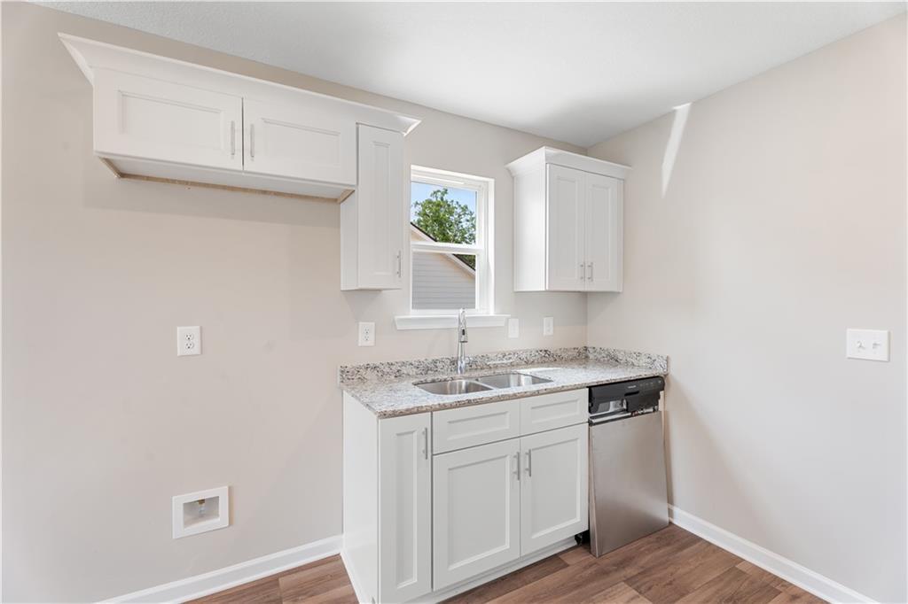 Modern white kitchen with granite countertops, stainless sink, dishwasher in Evermore Homes The Washington, Phenix City, Alabama