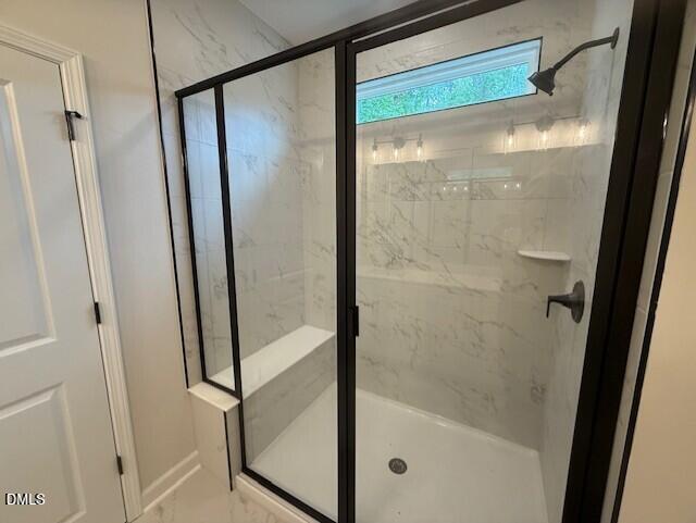 Walk-in shower with marble-look tile, built-in bench, and black frame in The Birch II A home, Montrose, Aberdeen, NC.