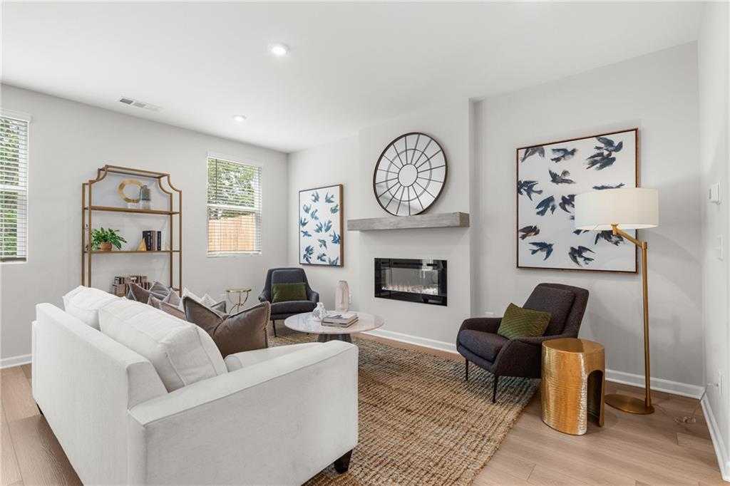 Cozy living room with white sectional sofa, gas fireplace, abstract bird art, large clock in Davidson Homes The Durant A, Emerson, Georgia