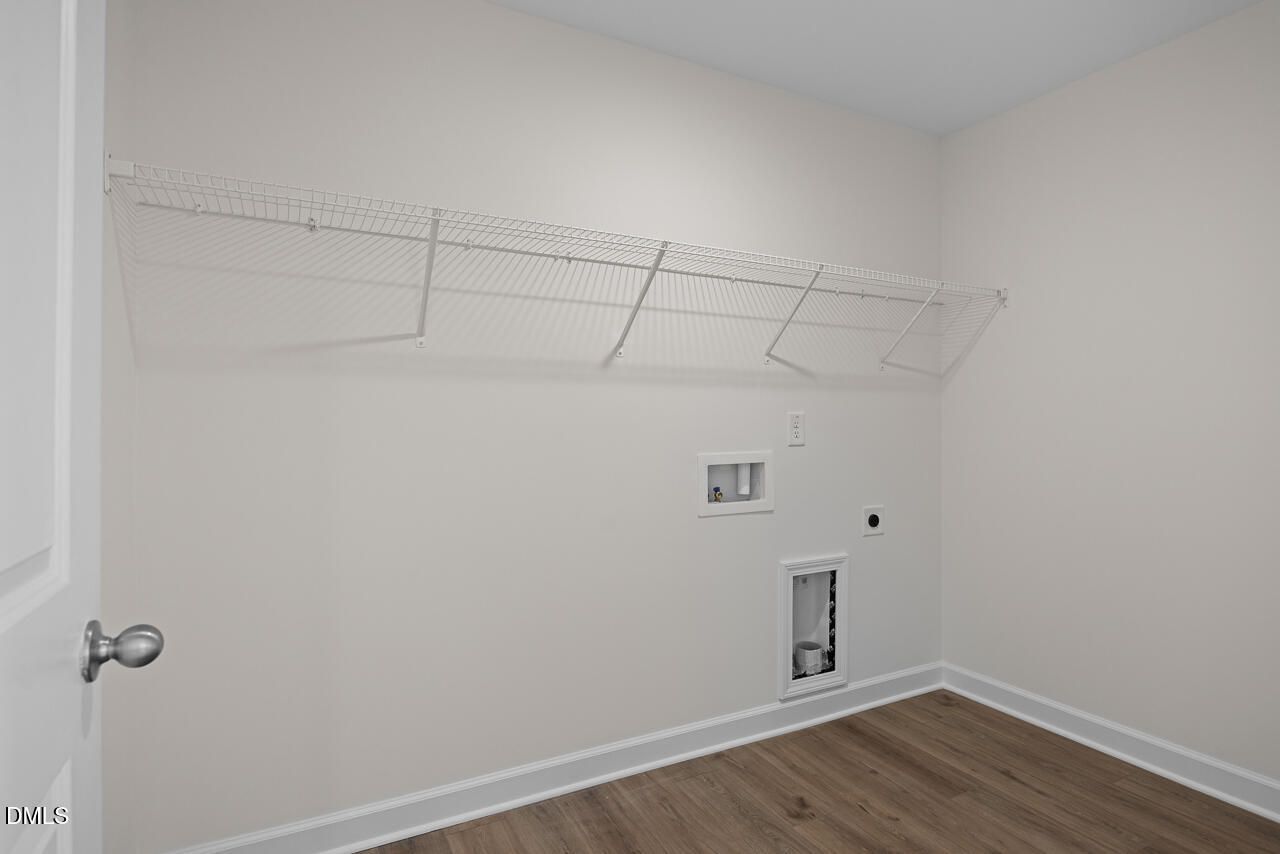Laundry room with wire shelving, washer hookups, and luxury vinyl plank flooring in Davidson Homes The Willow B, Zebulon NC