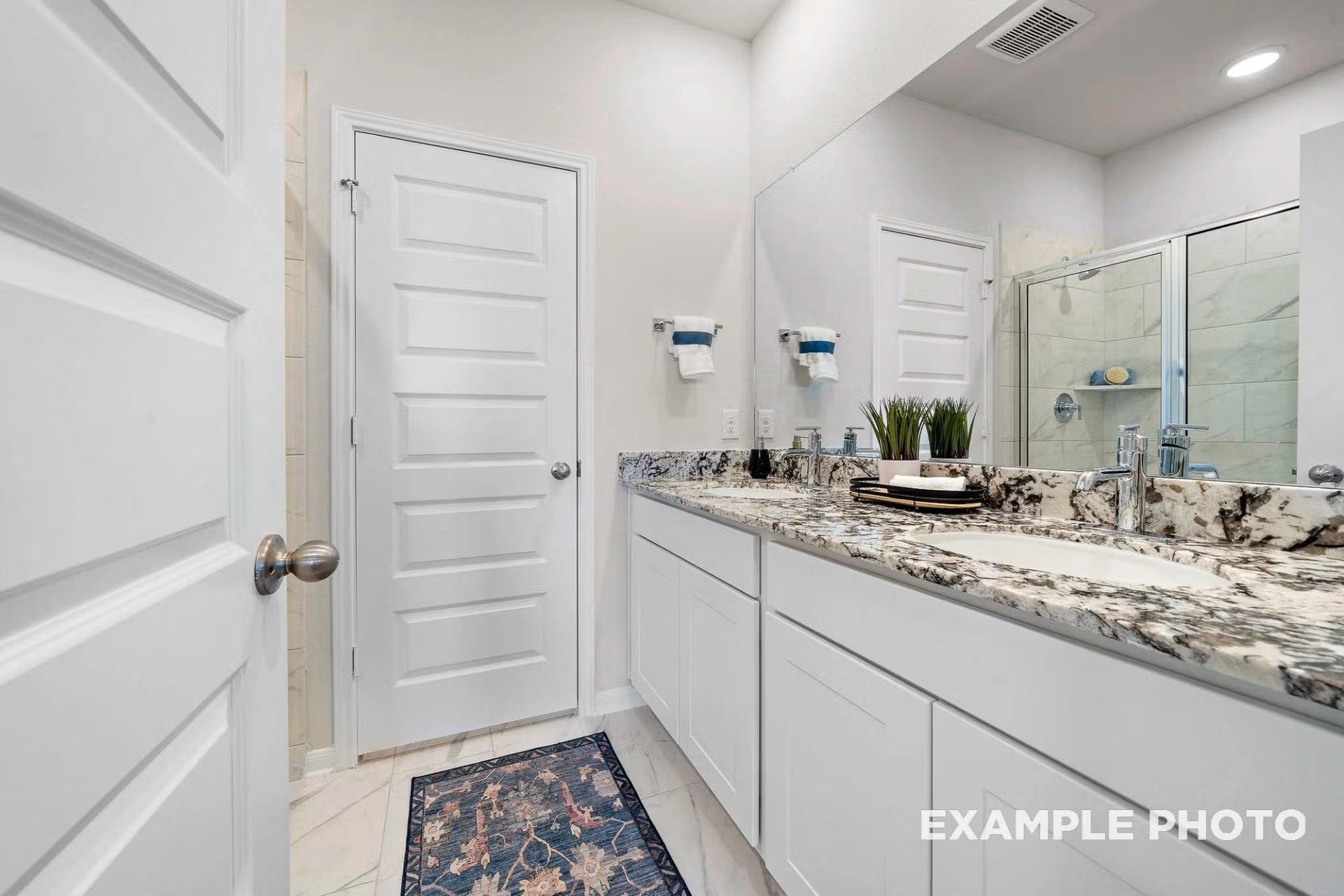 Modern bathroom with double vanity, granite countertops, and walk-in shower in The San Marcos E home in Heartland, Texas.