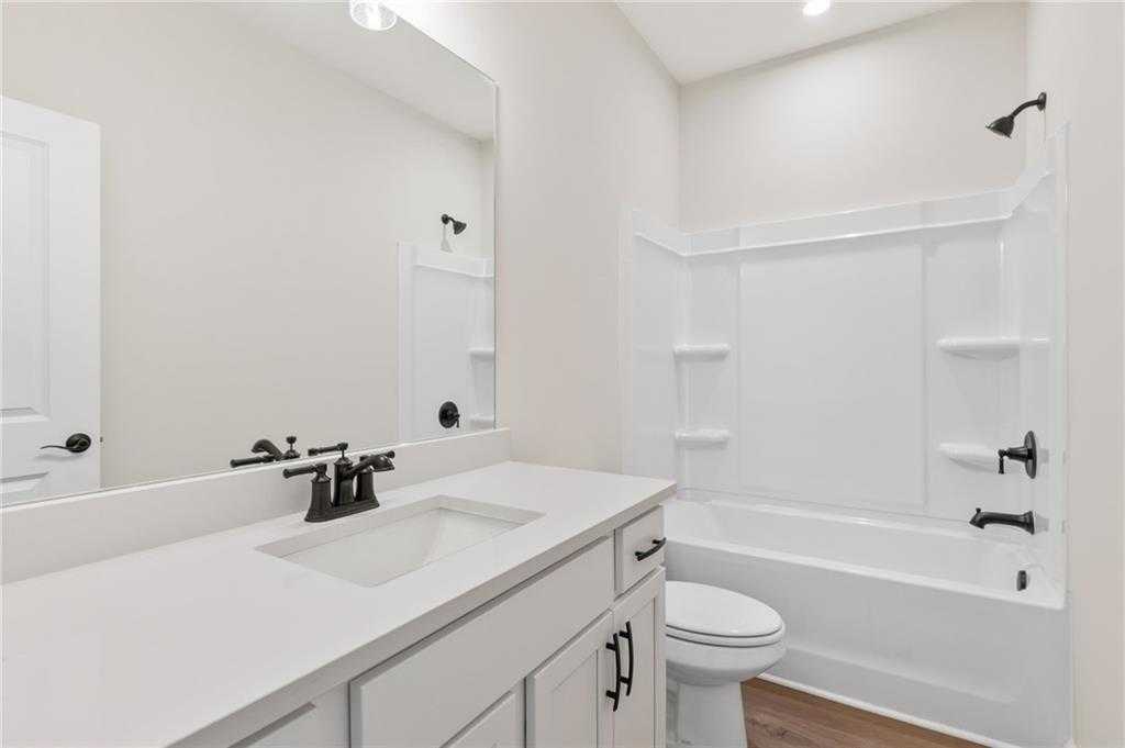 Bright bathroom with white vanity, single sink, soaking tub-shower combo, and toilet in Davidson Homes The Daphne B, Loganville, GA