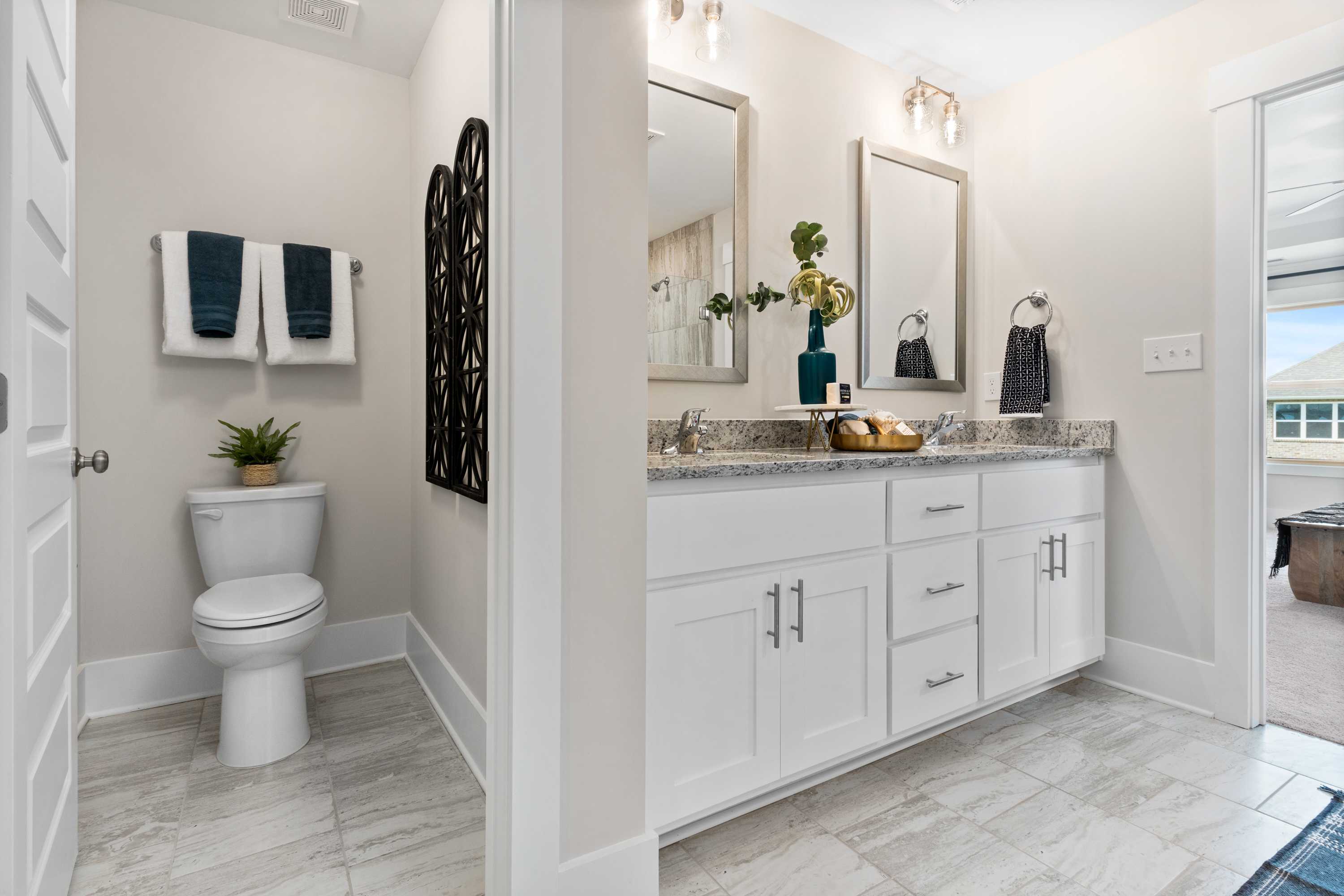 Spacious master bath in The Chelsea B with double vanity, white cabinets, mirrors, and tiled flooring