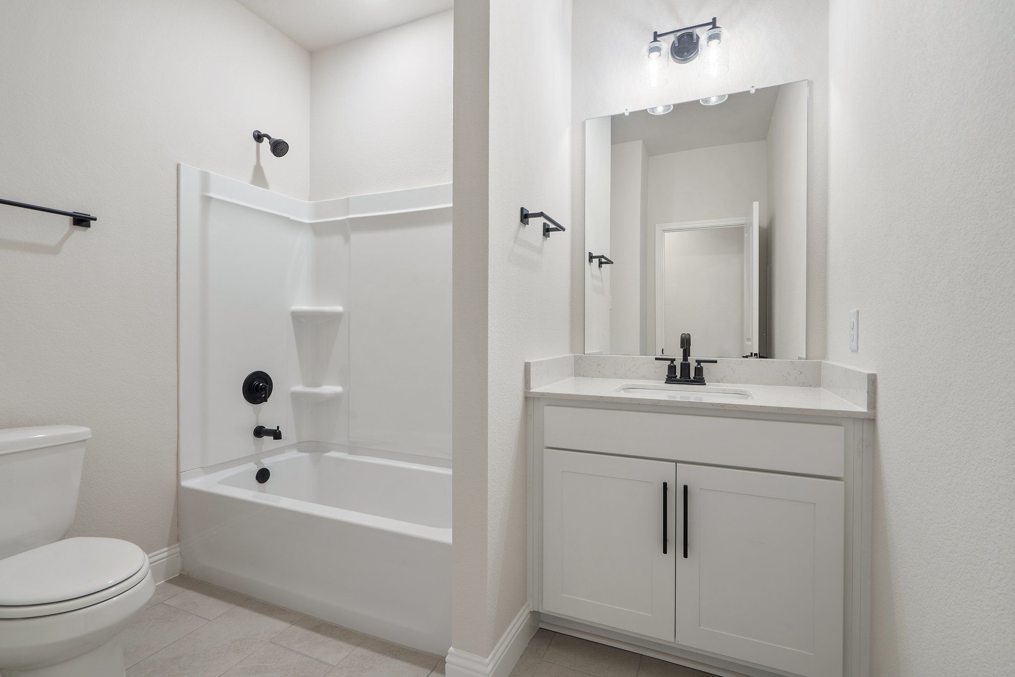 Modern bathroom in The Holly F home design featuring a white vanity, tub-shower combo, and sleek black fixtures.
