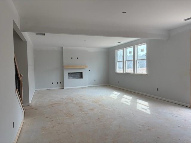 Spacious empty great room with wood mantel fireplace, large windows, and staircase in Davidson Homes The Hickory B, Winder, Georgia