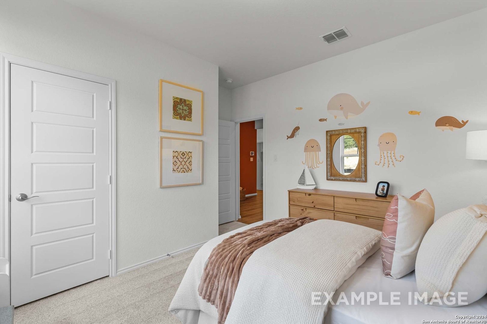 Whimsical children's bedroom with pink octopus decals, cozy bed, and wooden dresser in Davidson Homes The Daphne K, San Antonio