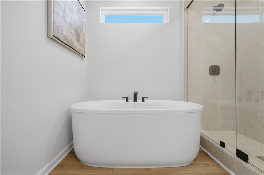 Freestanding soaking tub with matte black faucet beside glass walk-in shower in master bath of Davidson Homes Sinclair B, Cartersville