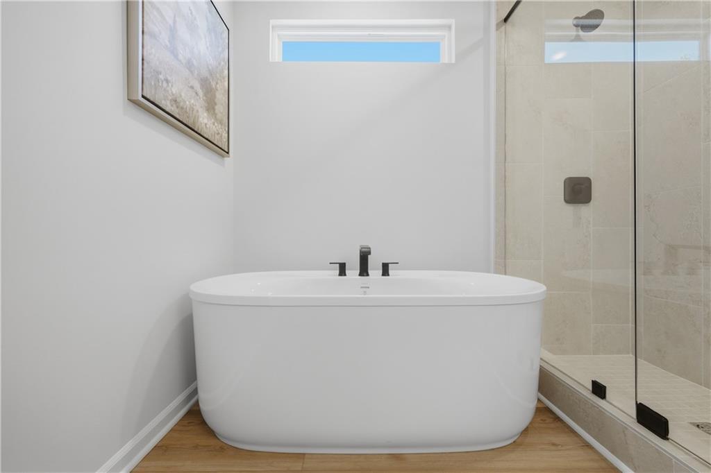 Freestanding soaking tub with matte black faucet beside glass walk-in shower in master bath of Davidson Homes Sinclair B, Cartersville