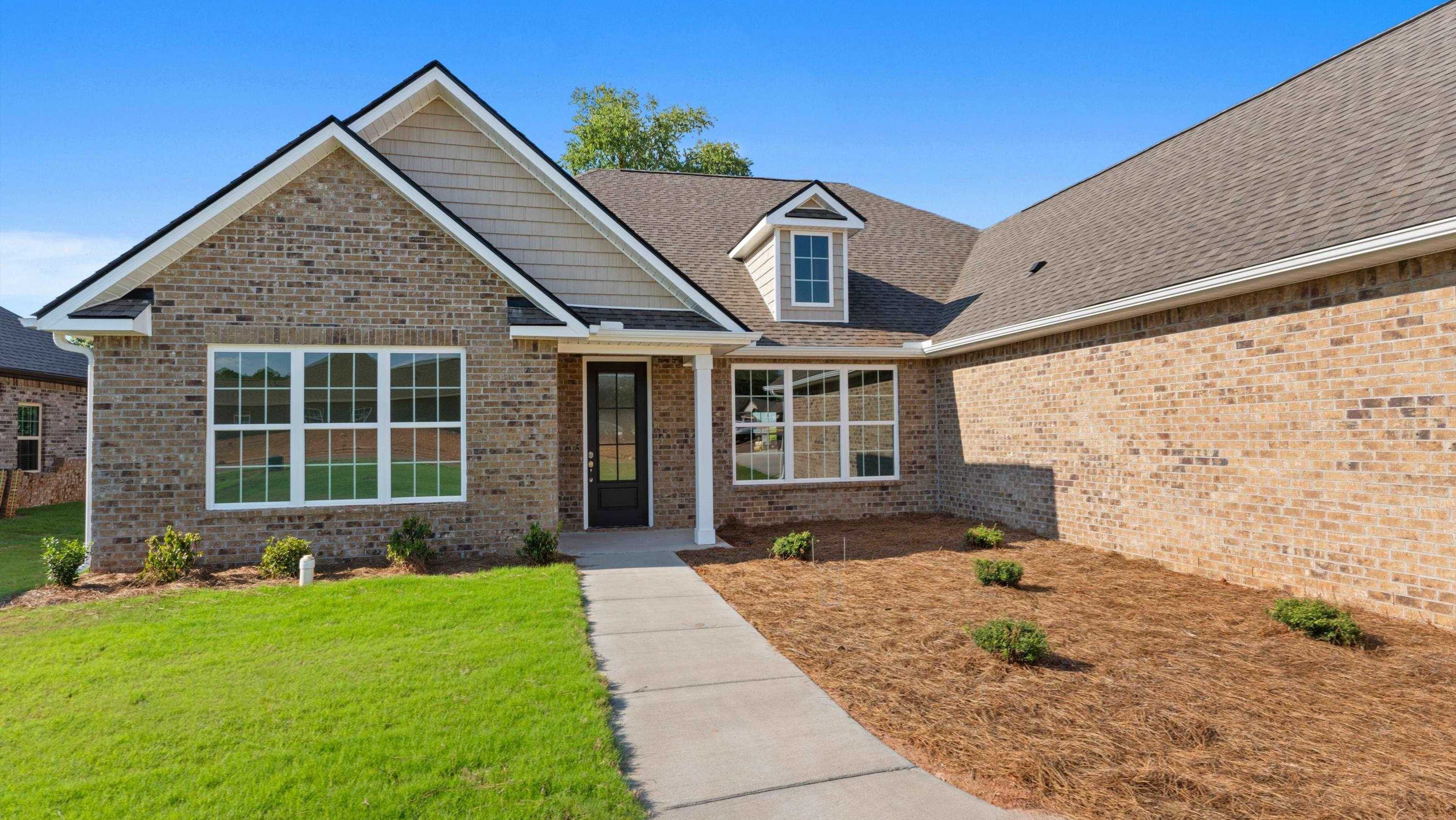 Brick model home at Davidson Homes open house, 29142 Canoe Circle, with gabled roof, front porch, large windows, and landscaped yard