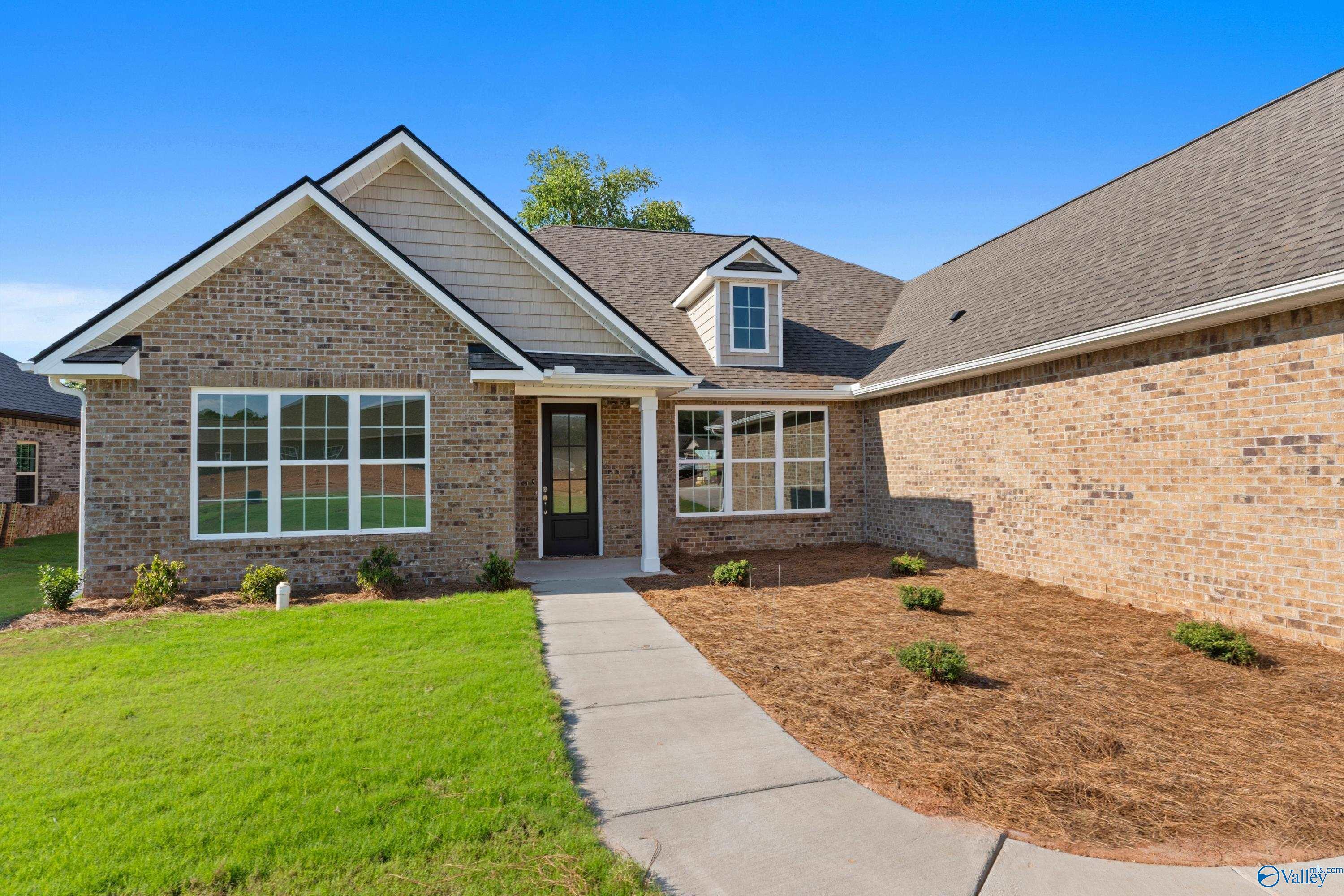 Charming brick one-story home with covered front porch, large windows, and landscaped yard in Creekside, Harvest, Alabama