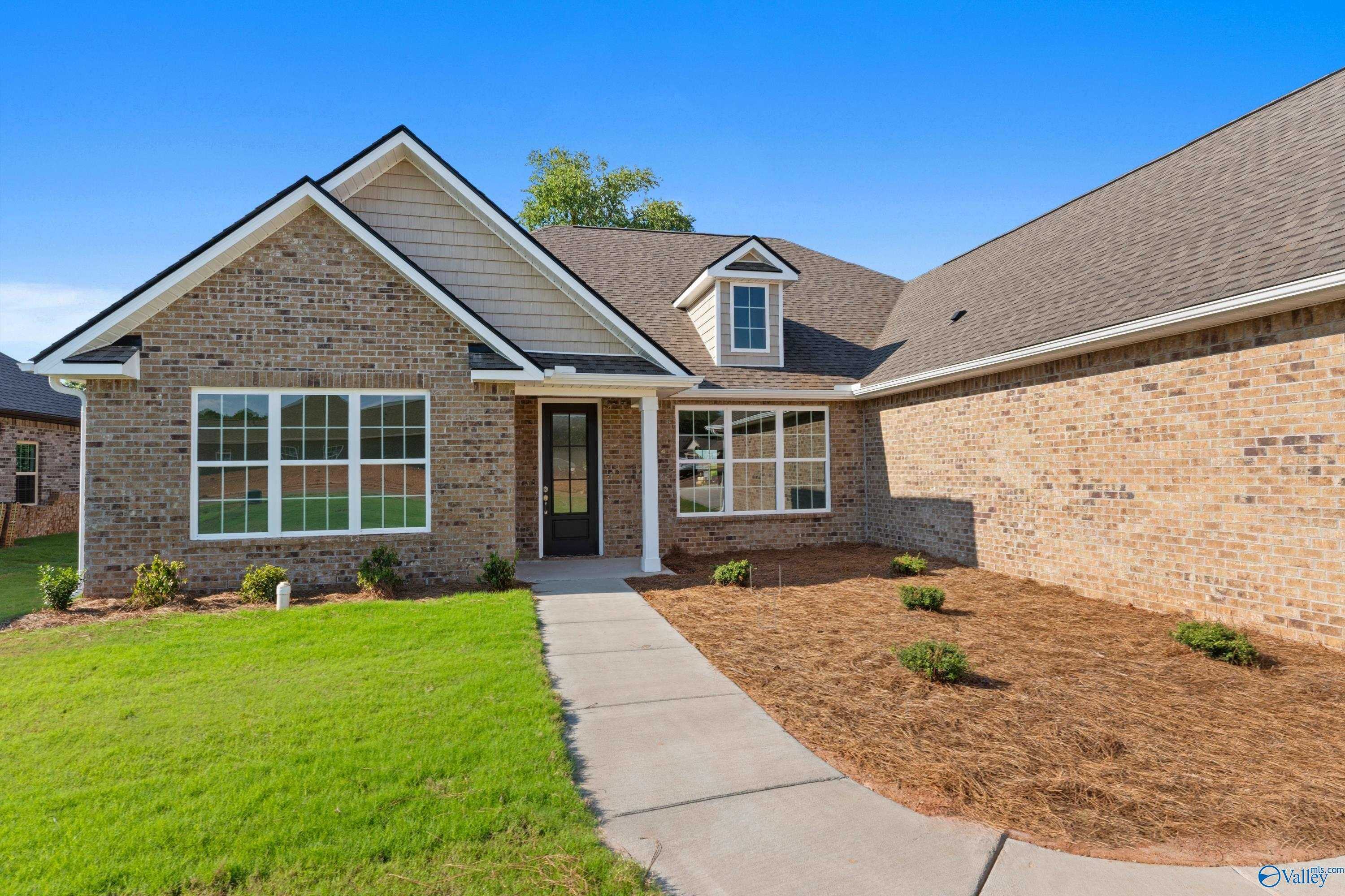 Charming brick one-story home with covered front porch, large windows, and landscaped yard in Creekside, Harvest, Alabama