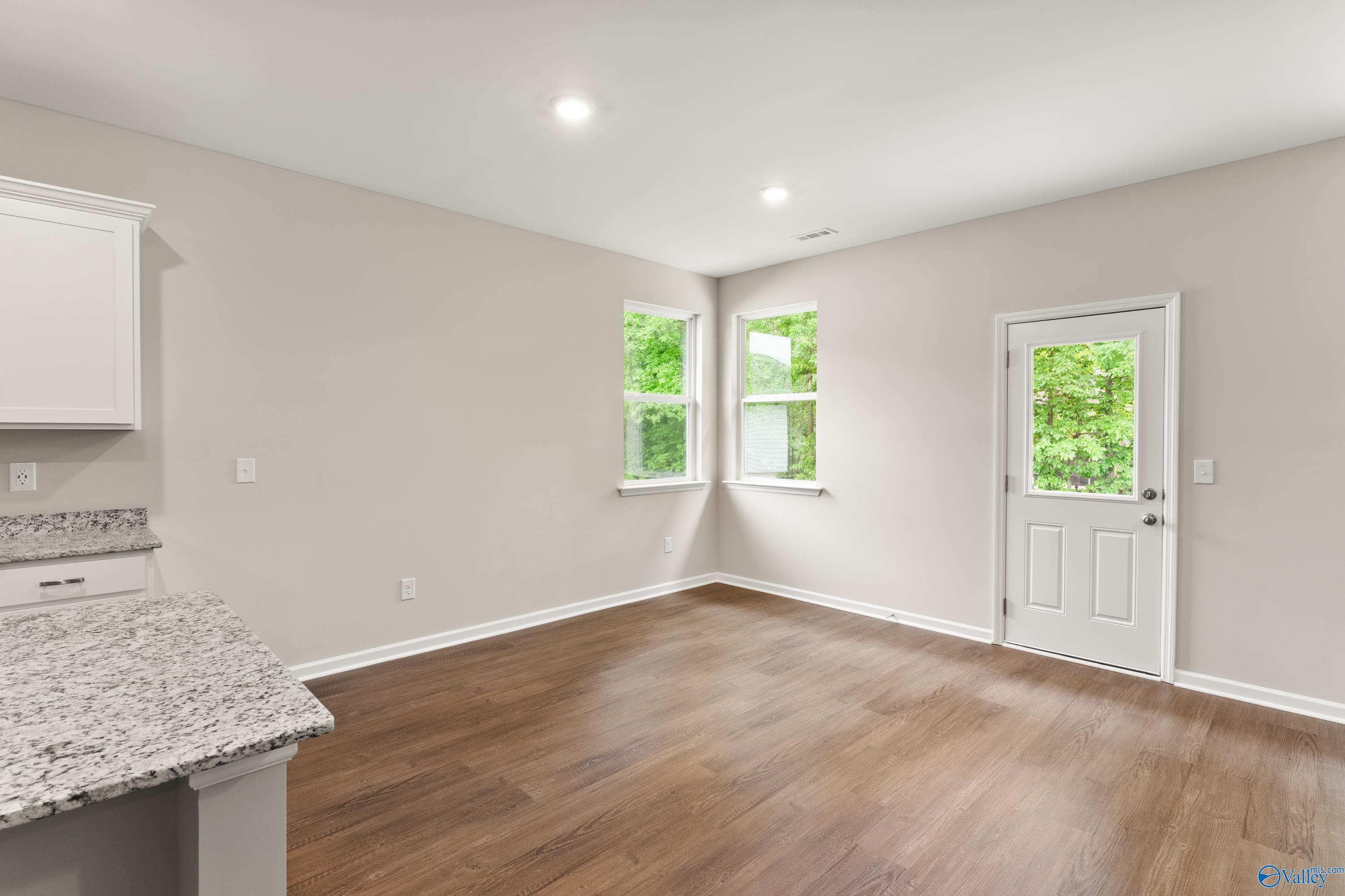 Bright utility room with granite counters, white cabinets, hardwood floors, and large windows in Davidson Homes The Phoenix, Fayetteville TN