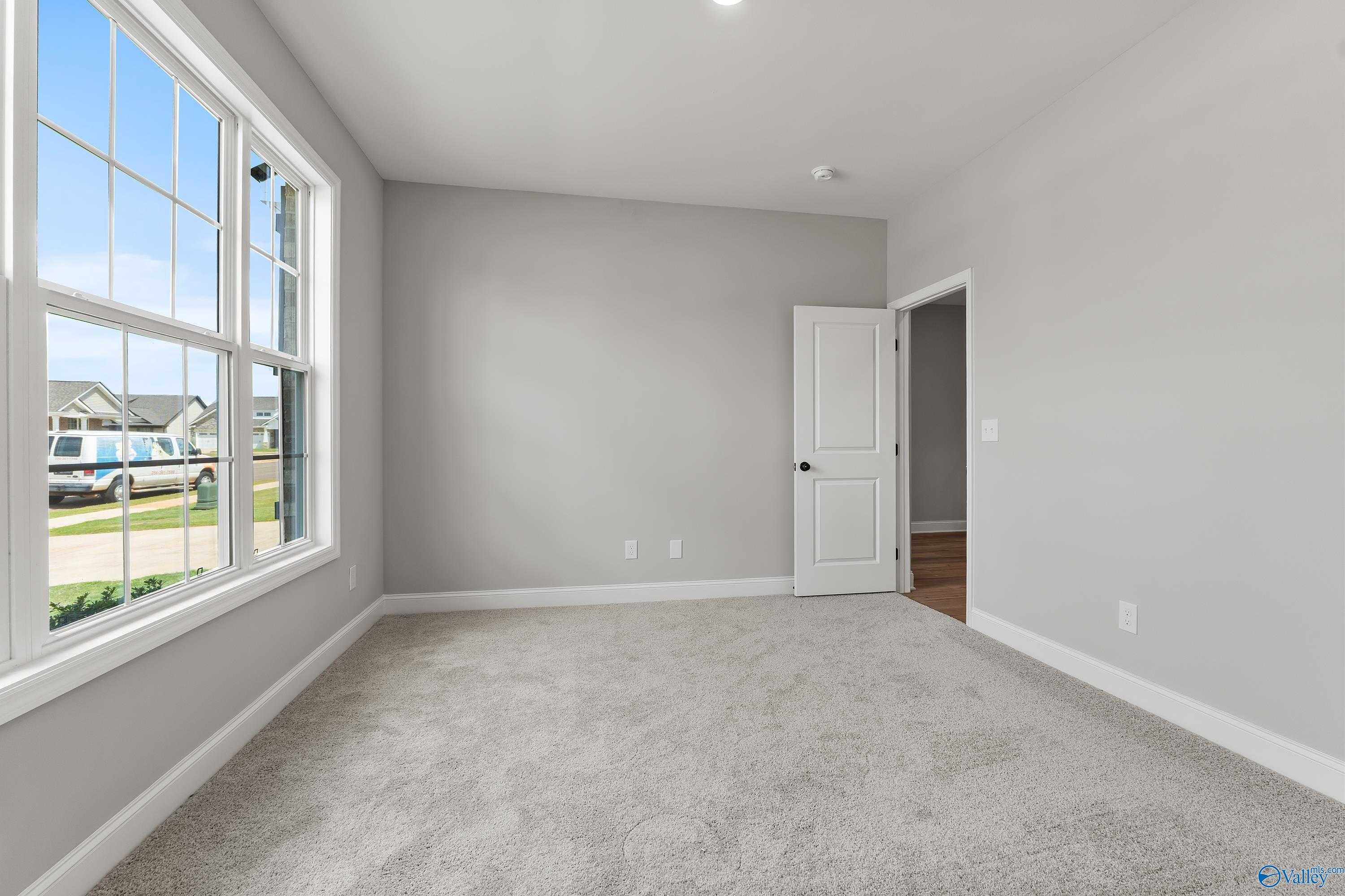 Bright bedroom with large windows, gray walls, and carpeted floor in Davidson Homes The Montgomery B With Bonus, Toney, Alabama
