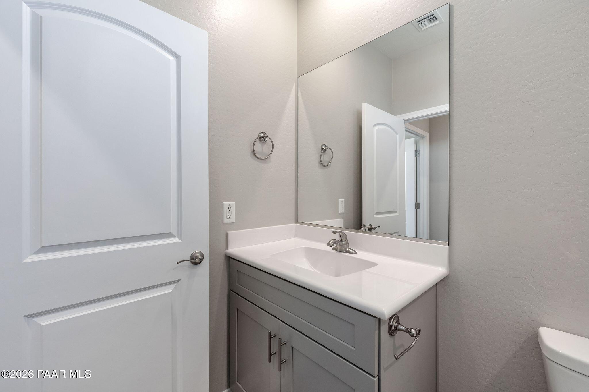 Guest bathroom with white vanity, quartz countertop, framed mirror, and neutral gray walls in Davidson Homes The Frontier A, Prescott Valley, AZ
