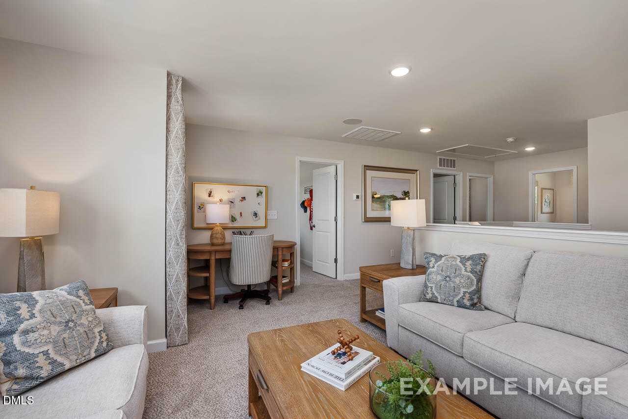 Cozy family room with gray sectional sofa, wooden coffee table, and corner desk in Davidson Homes The Willow B, Lillington NC
