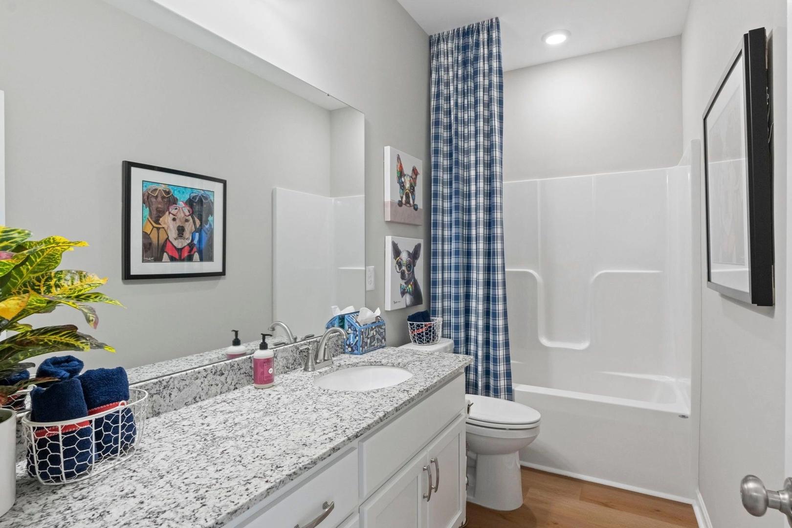 Modern bathroom at Bailey Park in Fayetteville TN with granite vanity, tub-shower combo, blue accents and hardwood floors