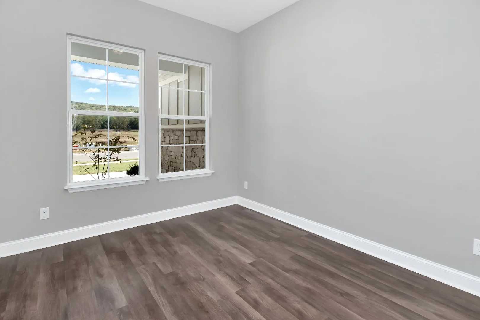 Spacious secondary bedroom in The Arcadia M with gray walls, large windows overlooking scenic view, and hardwood floors