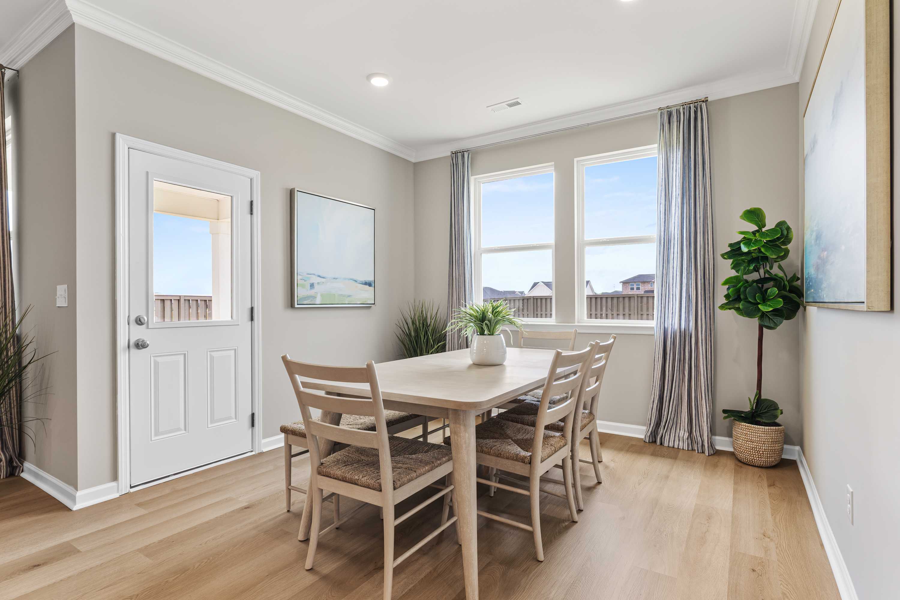 Dining room at The Meadows at Hampton Cove in Owens Cross Roads AL with oak table, chairs, fiddle leaf fig, and large windows