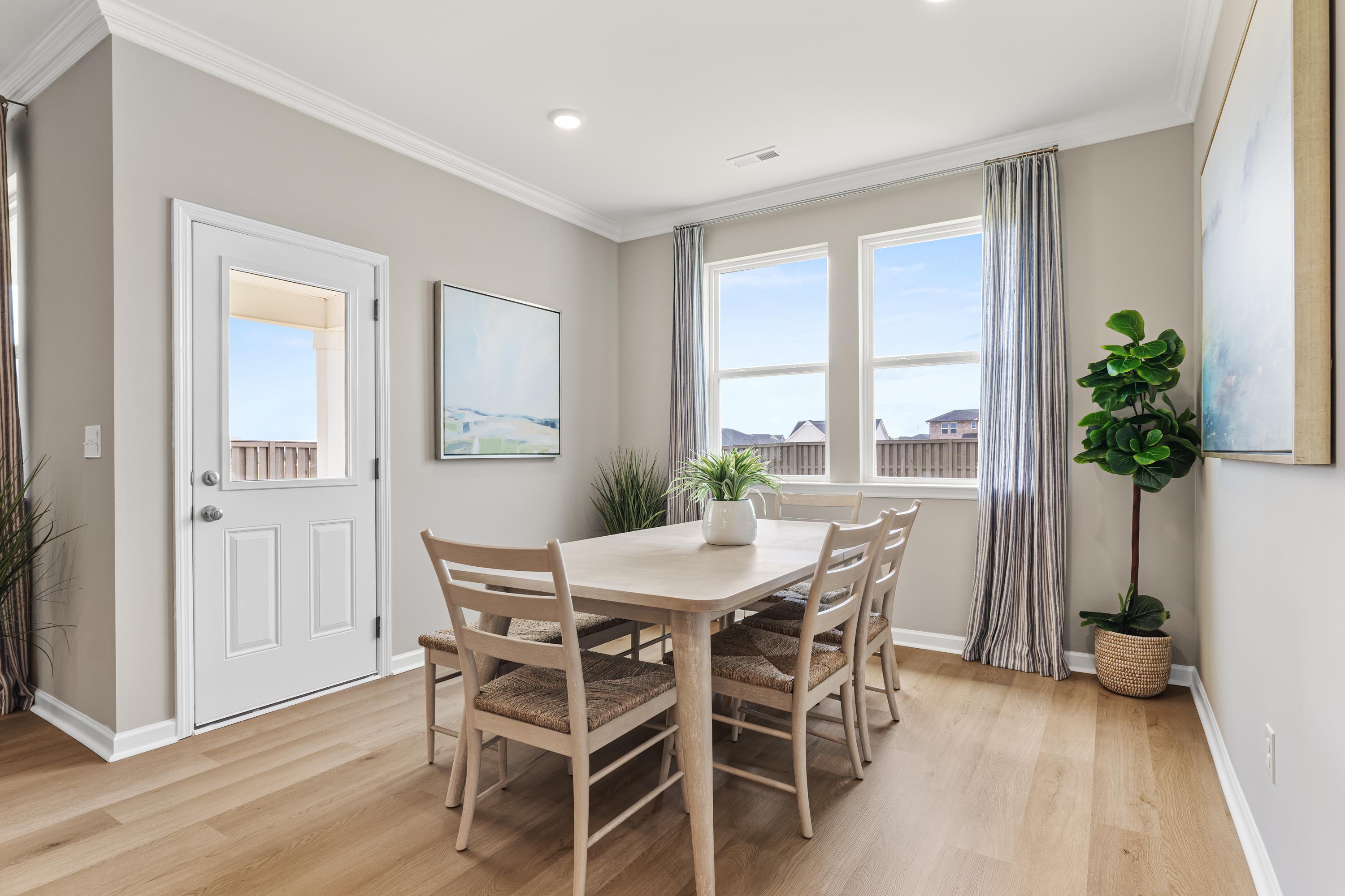 Dining room at The Meadows at Hampton Cove in Owens Cross Roads AL with oak table, chairs, fiddle leaf fig, and large windows