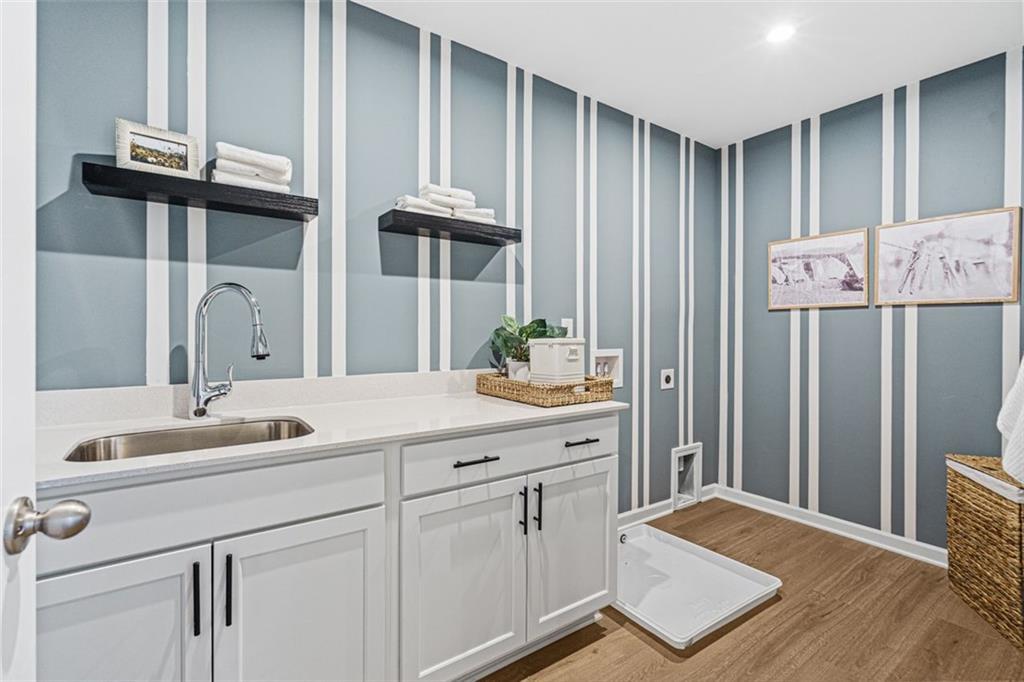 Modern laundry room with blue striped walls, white shaker cabinets, deep utility sink in Davidson Homes The Hickory B plan, Hoschton, GA