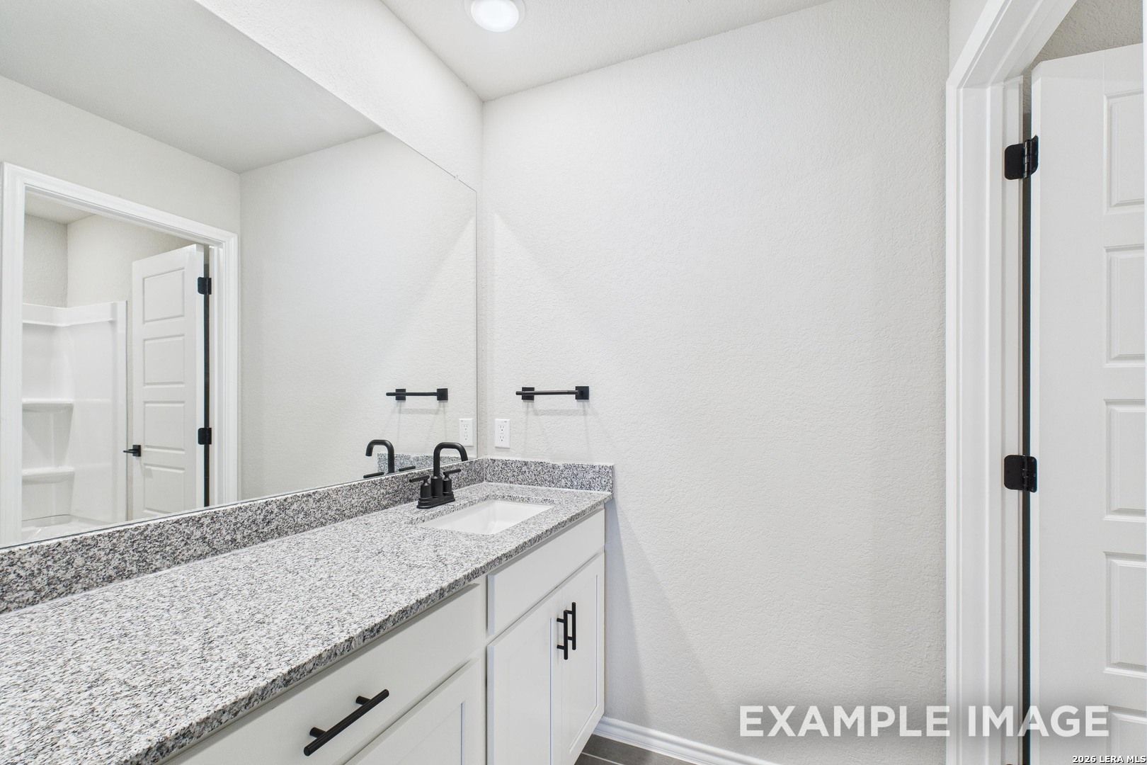 Modern bathroom vanity with granite countertop and black fixtures in The Charlotte B floor plan, Cedar Heights, San Antonio.