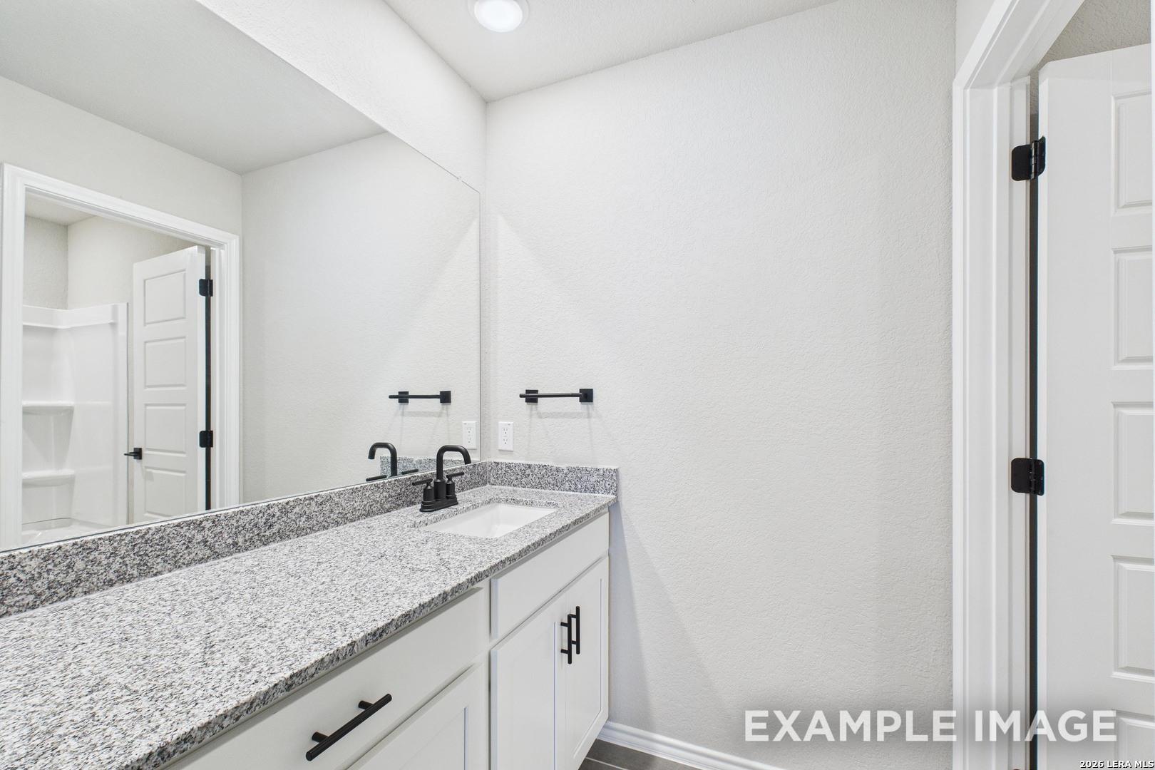 Modern bathroom vanity with granite countertop and black fixtures in The Charlotte B floor plan, Cedar Heights, San Antonio.