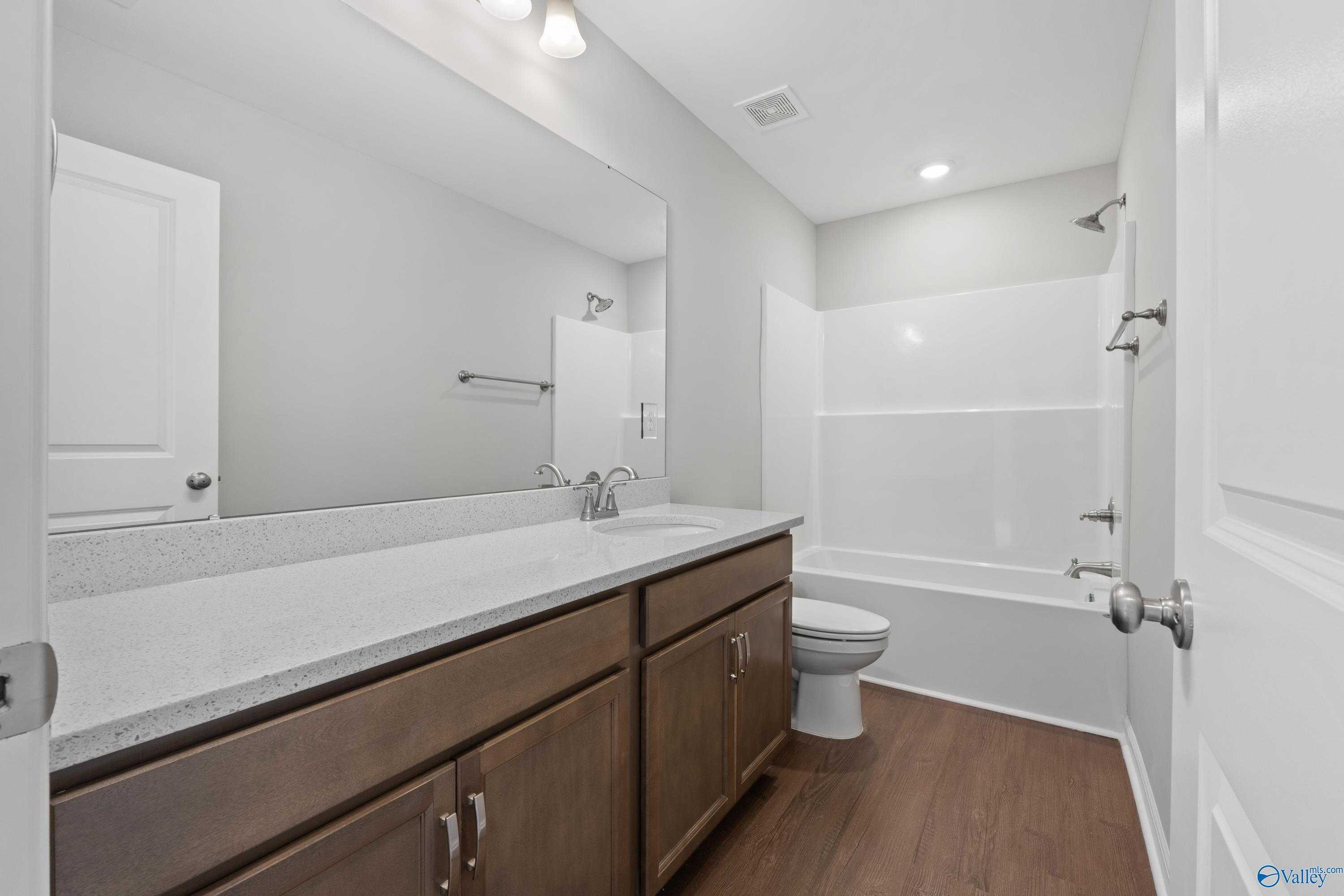 Contemporary master bath with granite double vanity, bathtub shower combo, and hardwood floors in Davidson Homes The Stella, Hazel Green, Alabama