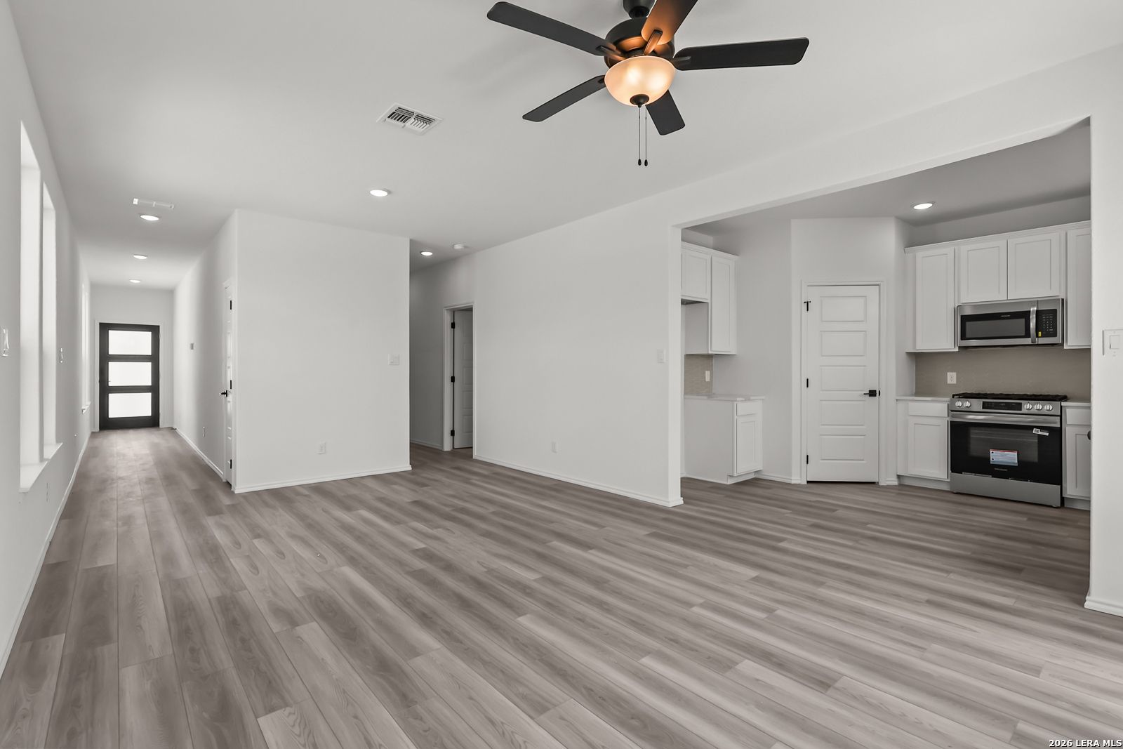Open-concept living room and kitchen with wood-look flooring in The Florence B floor plan, Meadows at Oak Creek, San Antonio.