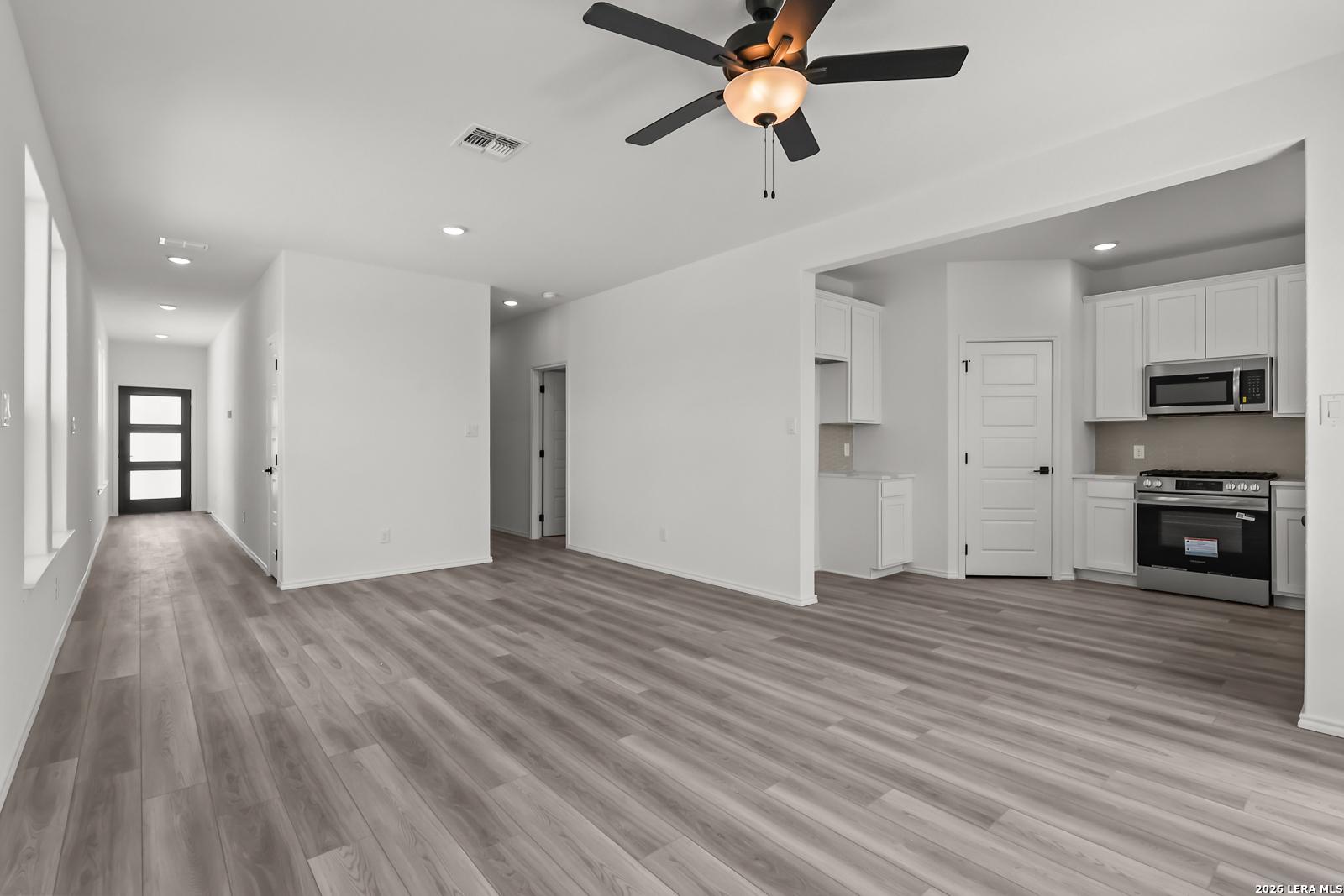 Open-concept living room and kitchen with wood-look flooring in The Florence B floor plan, Meadows at Oak Creek, San Antonio.