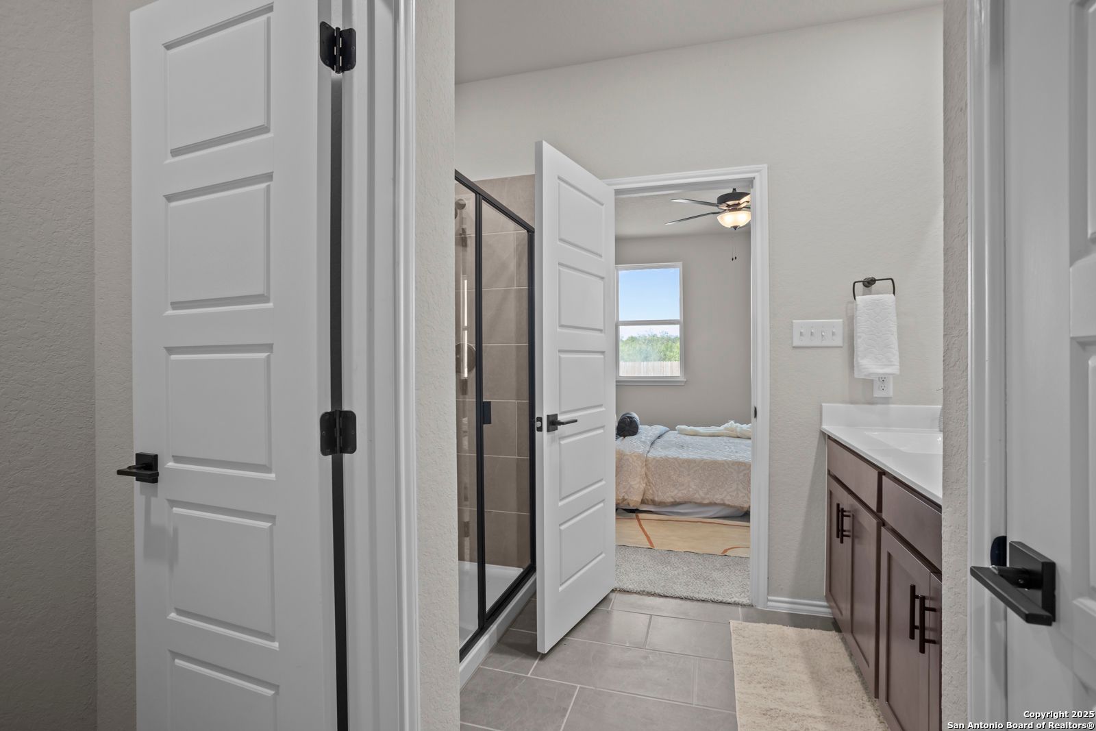 Modern master bathroom featuring walk-in shower, double vanity, and open door to bedroom in Davidson Homes The Asheville H, Converse, Texas