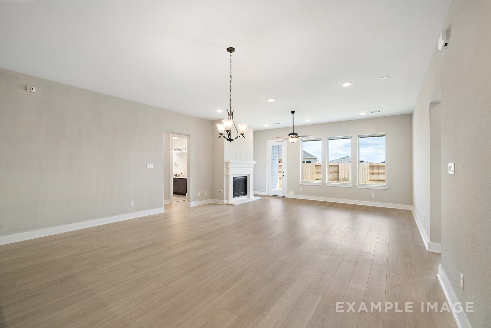 Spacious open-concept living area in The Elizabeth by Davidson Homes featuring fireplace, wood-look flooring, and large windows.
