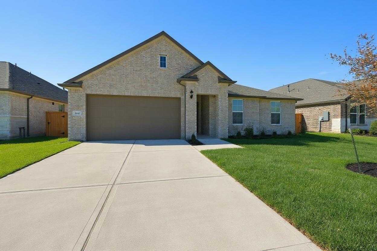 Single-story brick home with 2-car garage, concrete driveway, lush green lawn and tree in Lago Mar, Texas City, Texas - Davidson Homes Diana A