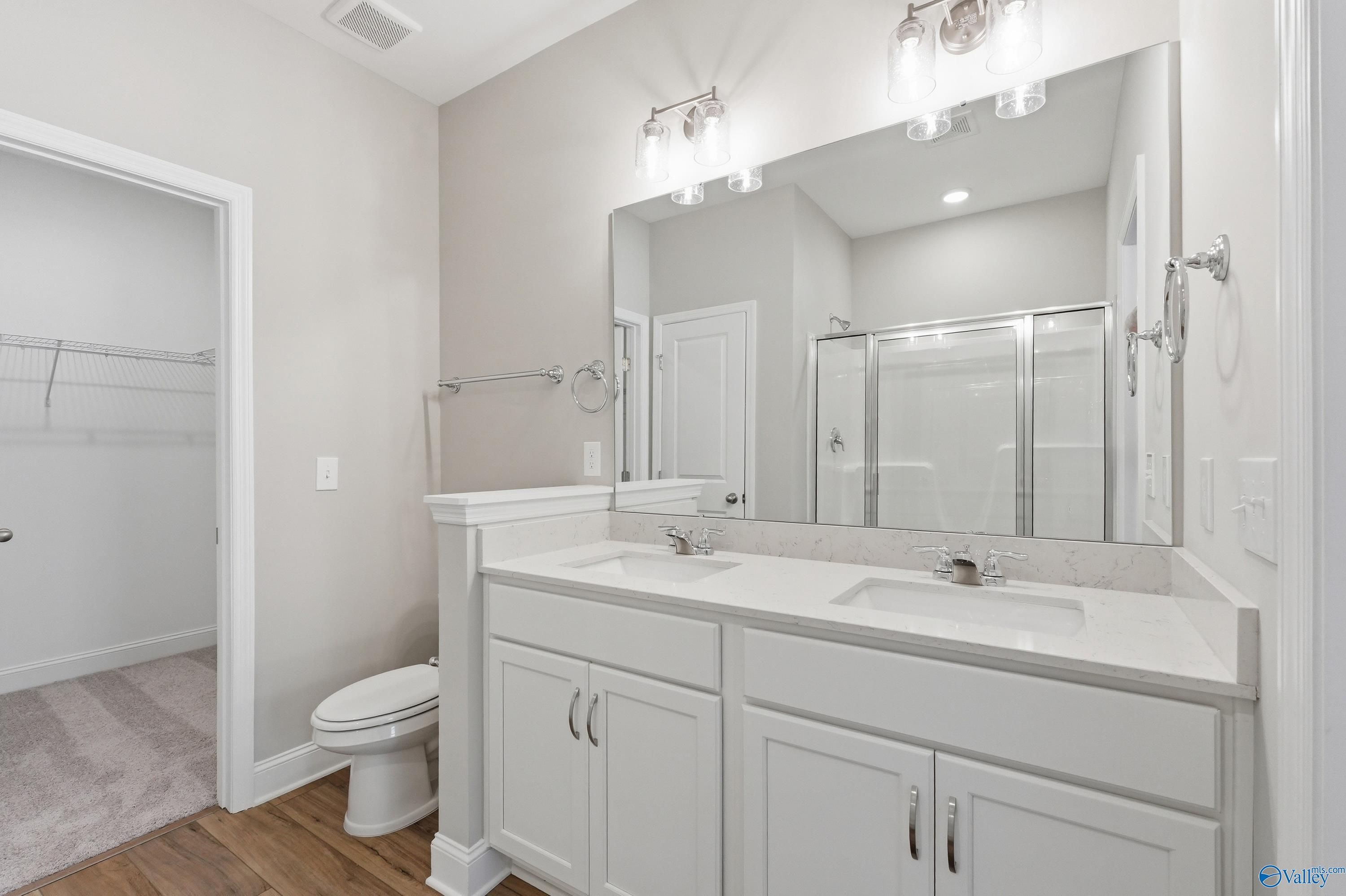 Modern master bathroom with double vanity, white cabinets, quartz counters, glass shower, and large mirror in Davidson Homes The Asheville, Huntsville AL