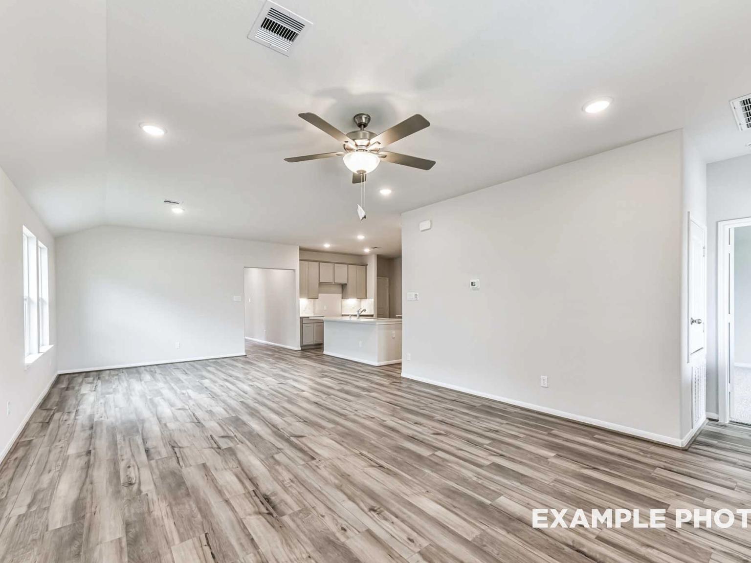 Open-concept living room with wood-look flooring in The Laguna C floor plan by Davidson Homes in River Ranch Meadows.