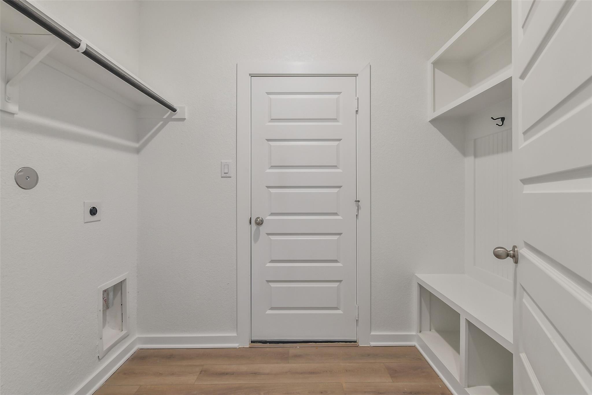 Bright laundry room with built-in shelves, hanging rod, storage bench, and utility hookups in Davidson Homes The Frio G, Cleveland, Texas