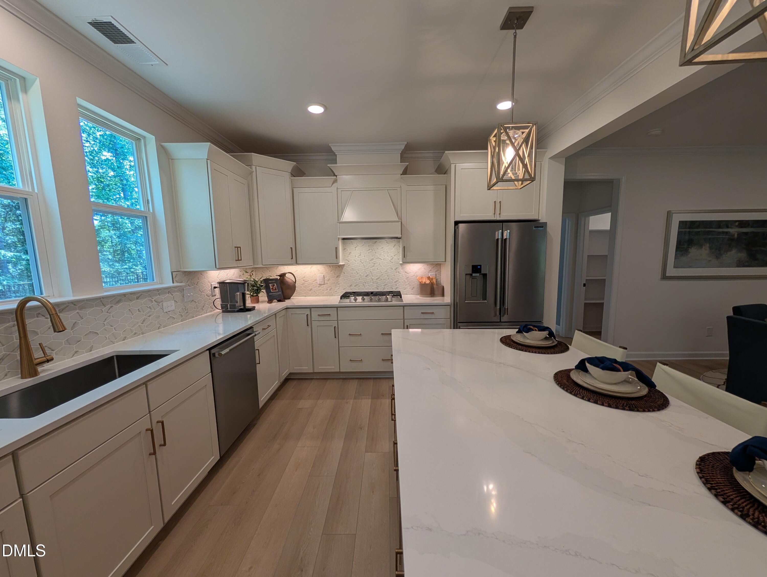 Modern kitchen with white cabinets, quartz island, and stainless appliances in The Aspen B home at Wendell Ridge, NC.