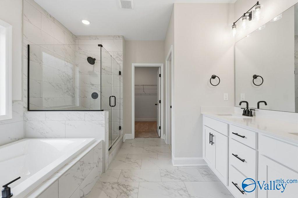 Modern master bathroom featuring marble tile floors, glass walk-in shower, freestanding tub, and double vanity in Davidson Homes The Rockford B, Hartselle, AL