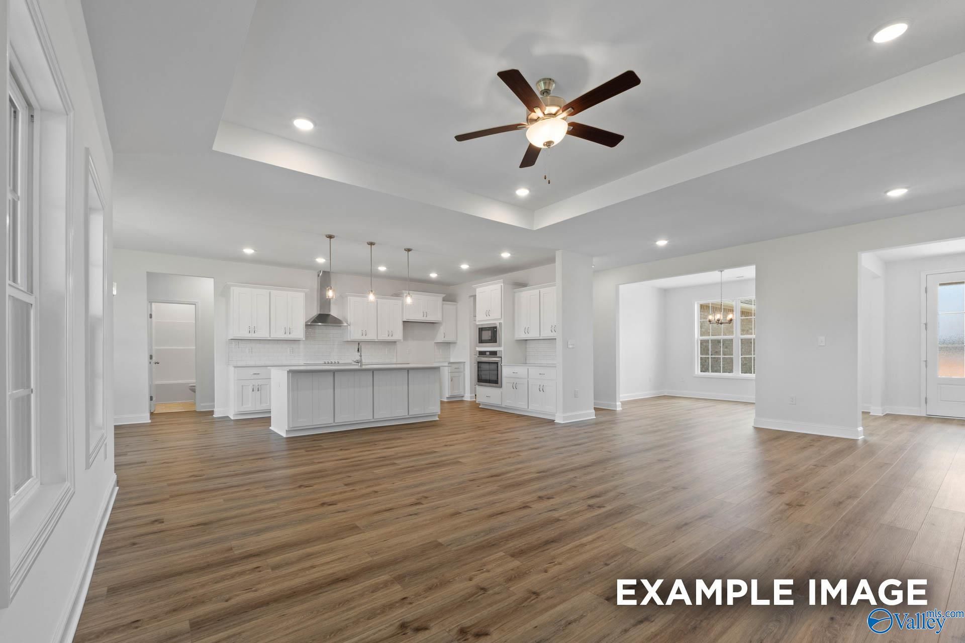 Spacious open-concept kitchen with white cabinets, large island, pendant lights, and ceiling fan in Davidson Homes The Oxford, Huntsville, Alabama